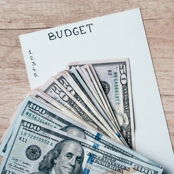 An image of dollar bills, and a paper with the word 'Budget'.