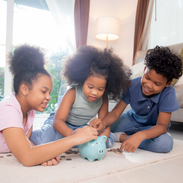 An image of three children putting coins in a piggy bank.